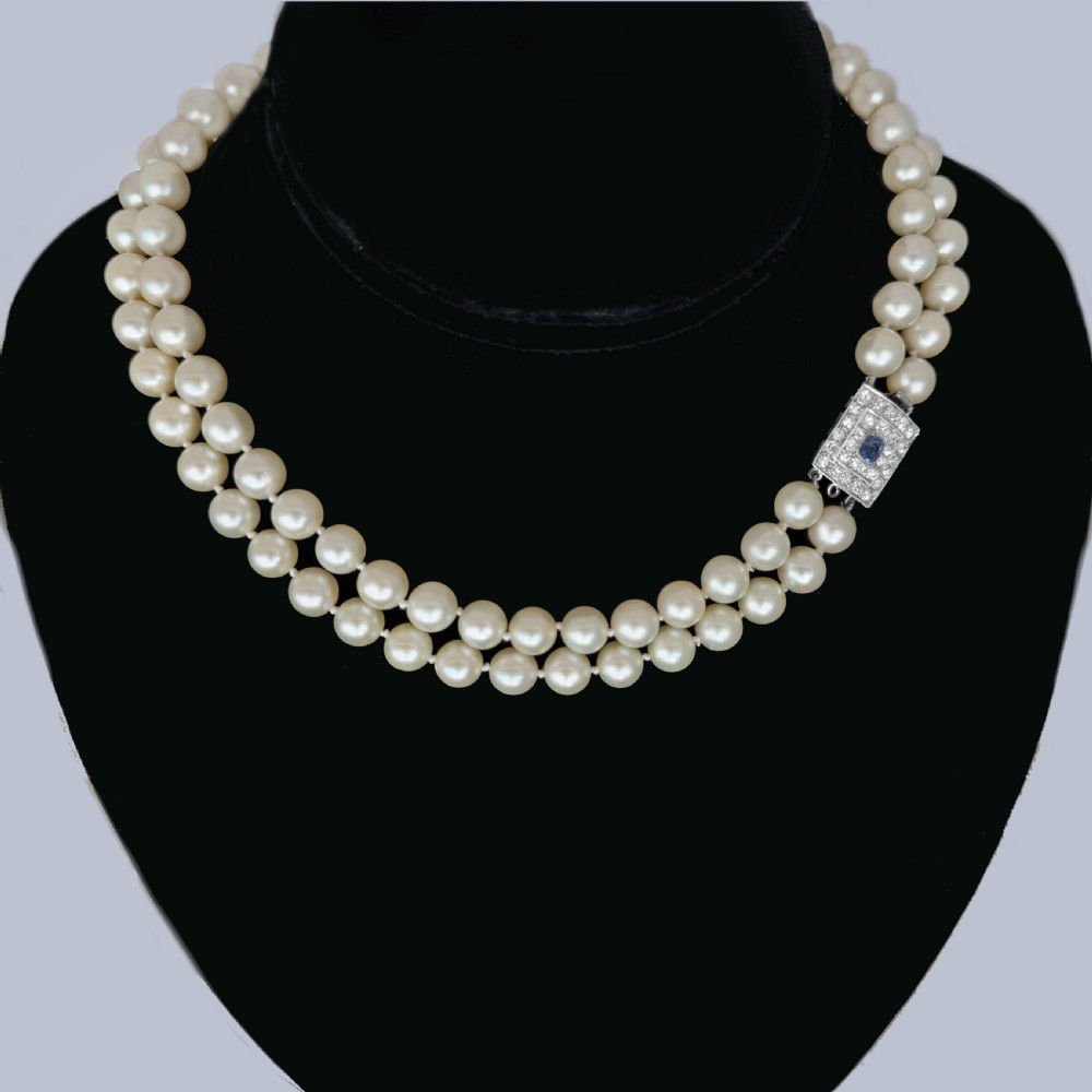 A double strand cream pearl necklace featuring a square 18ct white gold clasp set with a central square blue sapphire and accent diamonds. View VII