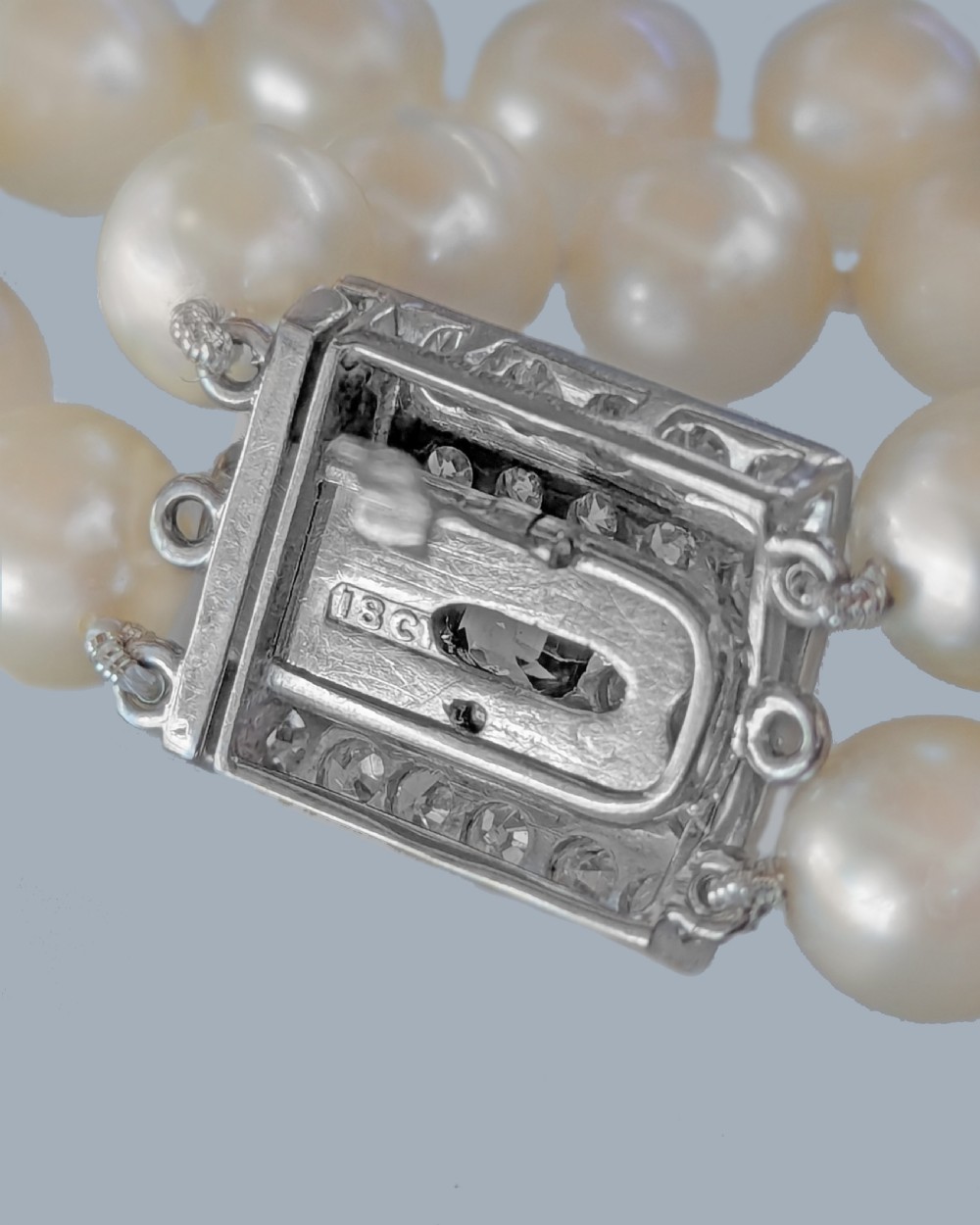 A double strand cream pearl necklace featuring a square 18ct white gold clasp set with a central square blue sapphire and accent diamonds. View X