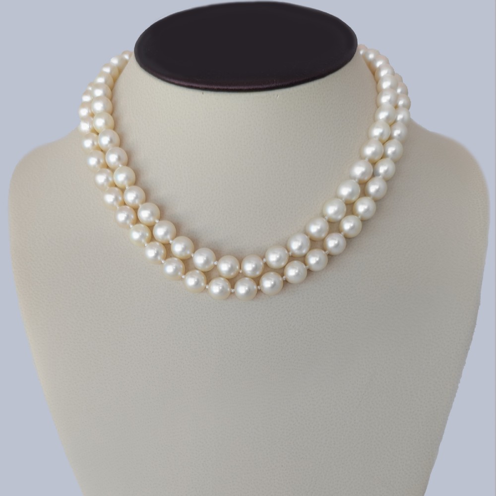 A double strand cream pearl necklace featuring a square 18ct white gold clasp set with a central square blue sapphire and accent diamonds. View XII