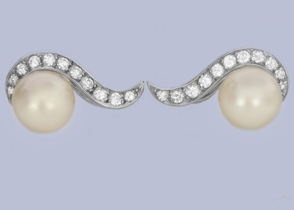 A pair of 18ct white gold stud earrings featuring round cream pearls accented with sweeping bands of grain-set diamonds. View X