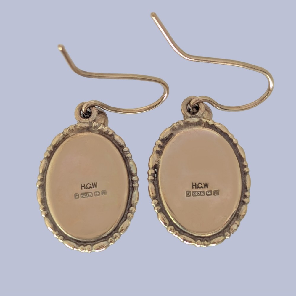 Pair of vintage 9ct gold drop earrings featuring oval cabochon purple amethysts set in decorative gold borders with shepherds hook wires. View III