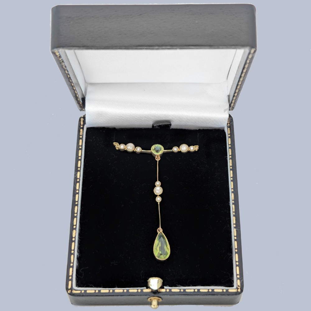 An Edwardian 15ct gold lavalier pendant necklace featuring a central round peridot, seed pearl accents, and a suspended pear-cut peridot drop. View VIII
