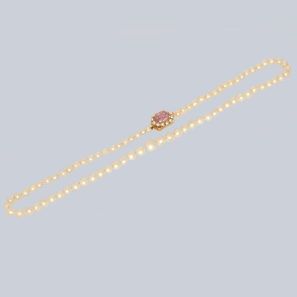 A single strand of cream cultured pearls featuring an oval purple amethyst mounted in a 9ct gold clasp surrounded by small pearls.