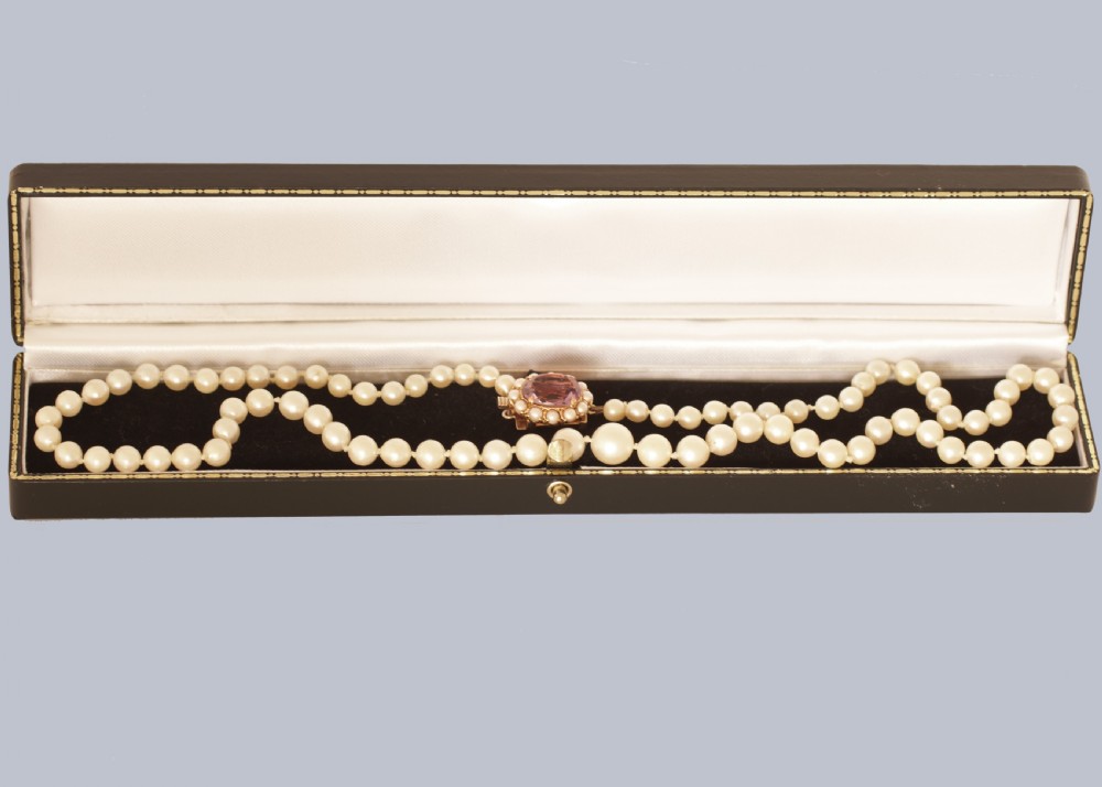 A single strand of cream cultured pearls featuring an oval purple amethyst mounted in a 9ct gold clasp surrounded by small pearls. View VI