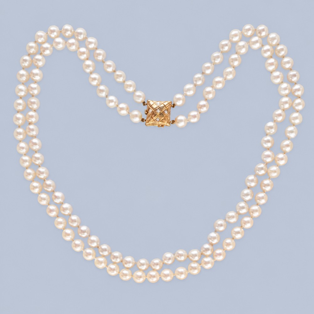 A double strand cultured pearl necklace featuring a square textured gold clasp embellished with diamonds.
