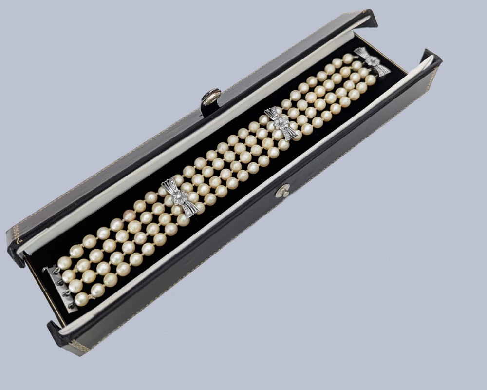 A vintage four-strand cultured pearl bracelet connected by three white gold bow-shaped spacers set with small diamonds. View VI
