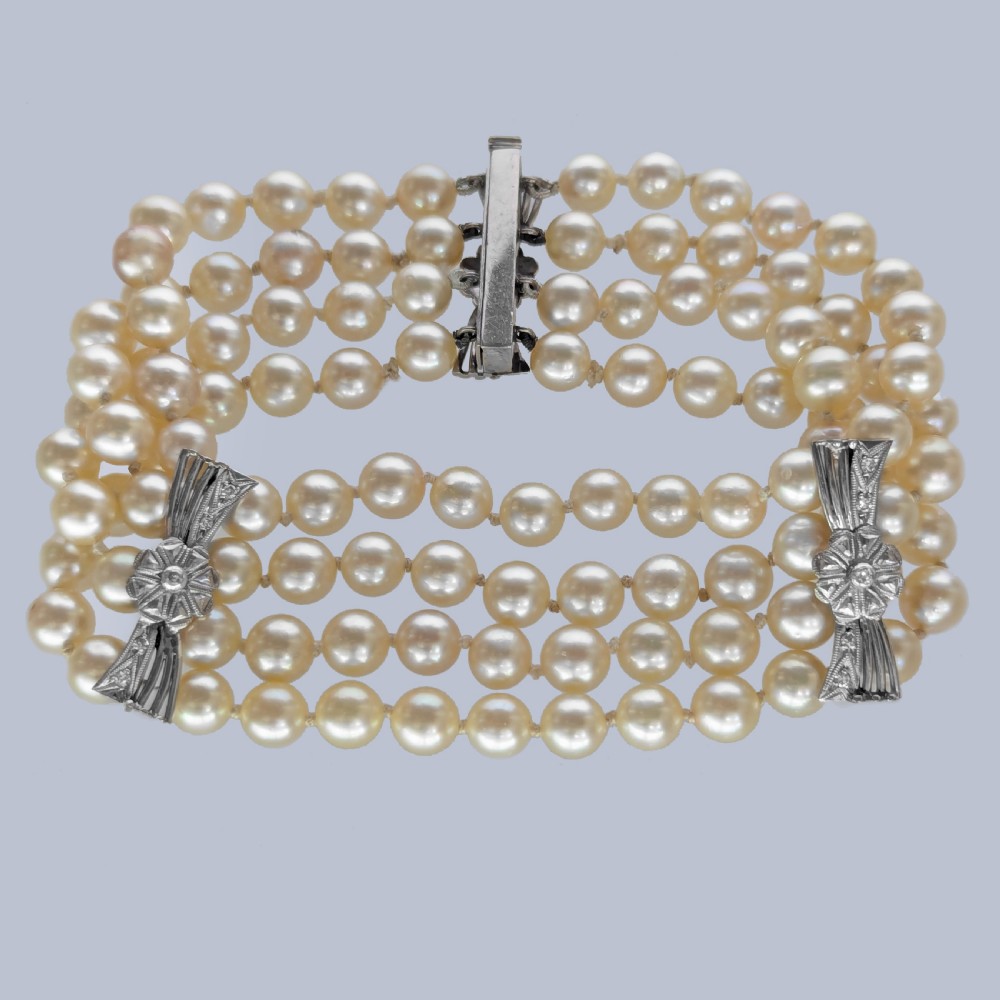 A vintage four-strand cultured pearl bracelet connected by three white gold bow-shaped spacers set with small diamonds. View VII