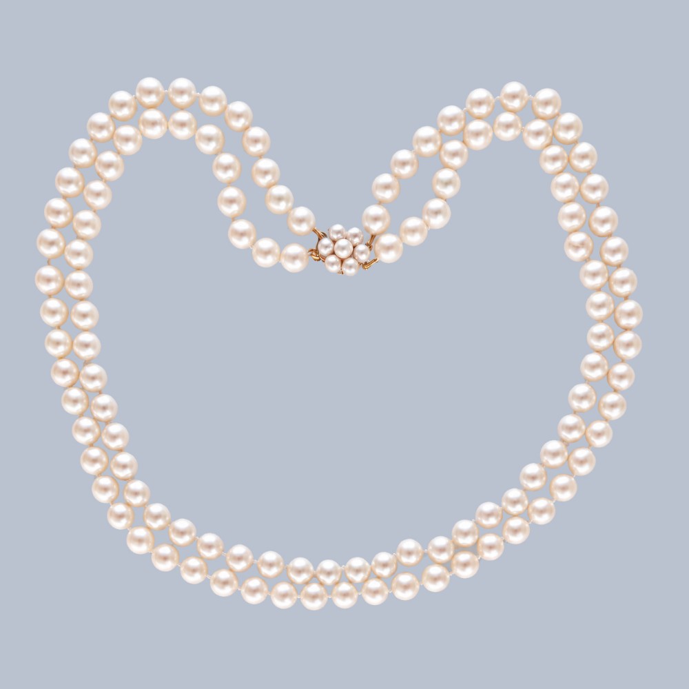 A double-strand cultured pearl necklace featuring uniform cream pearls fastened with a floral cluster gold clasp.