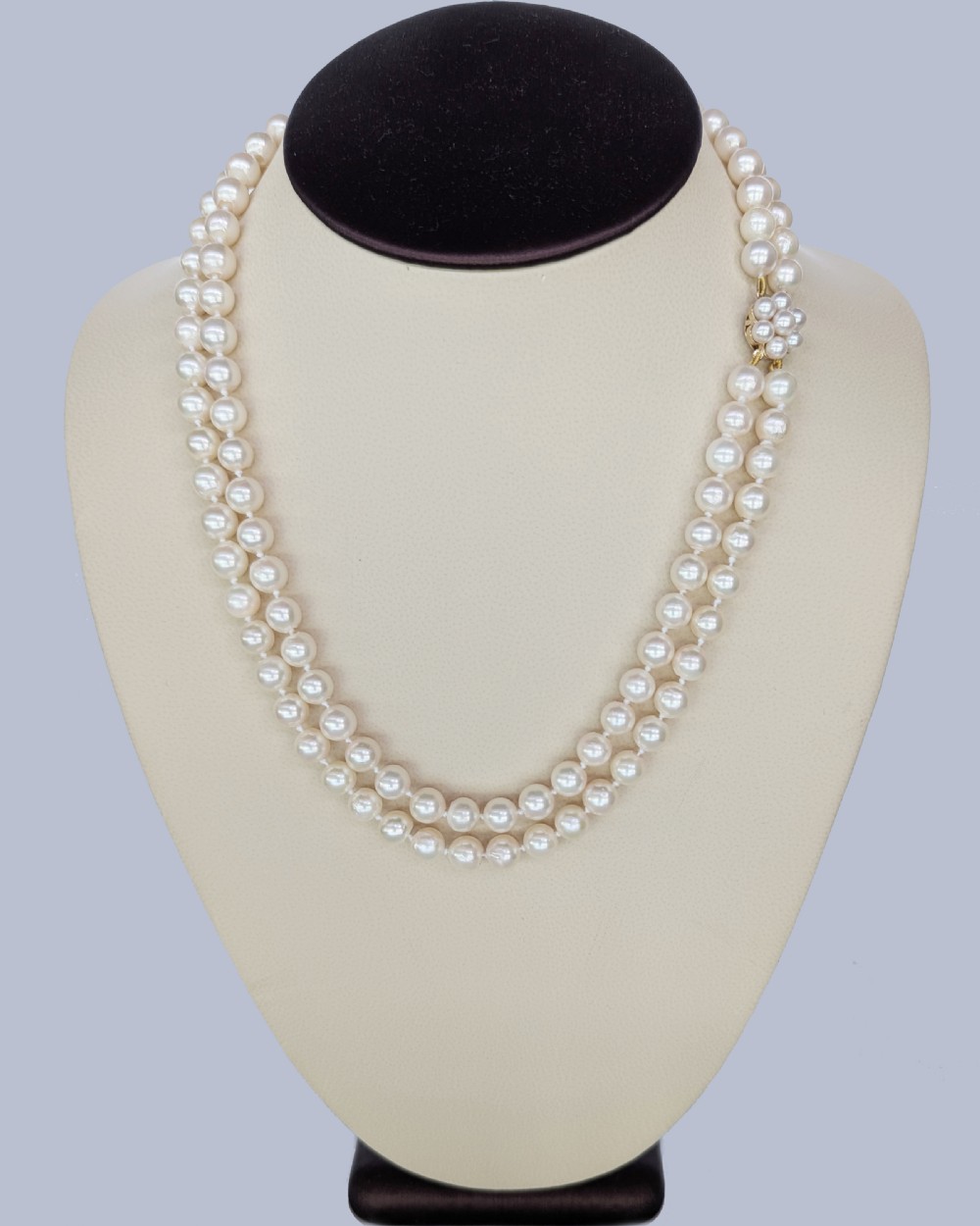 A double-strand cultured pearl necklace featuring uniform cream pearls fastened with a floral cluster gold clasp. View IV