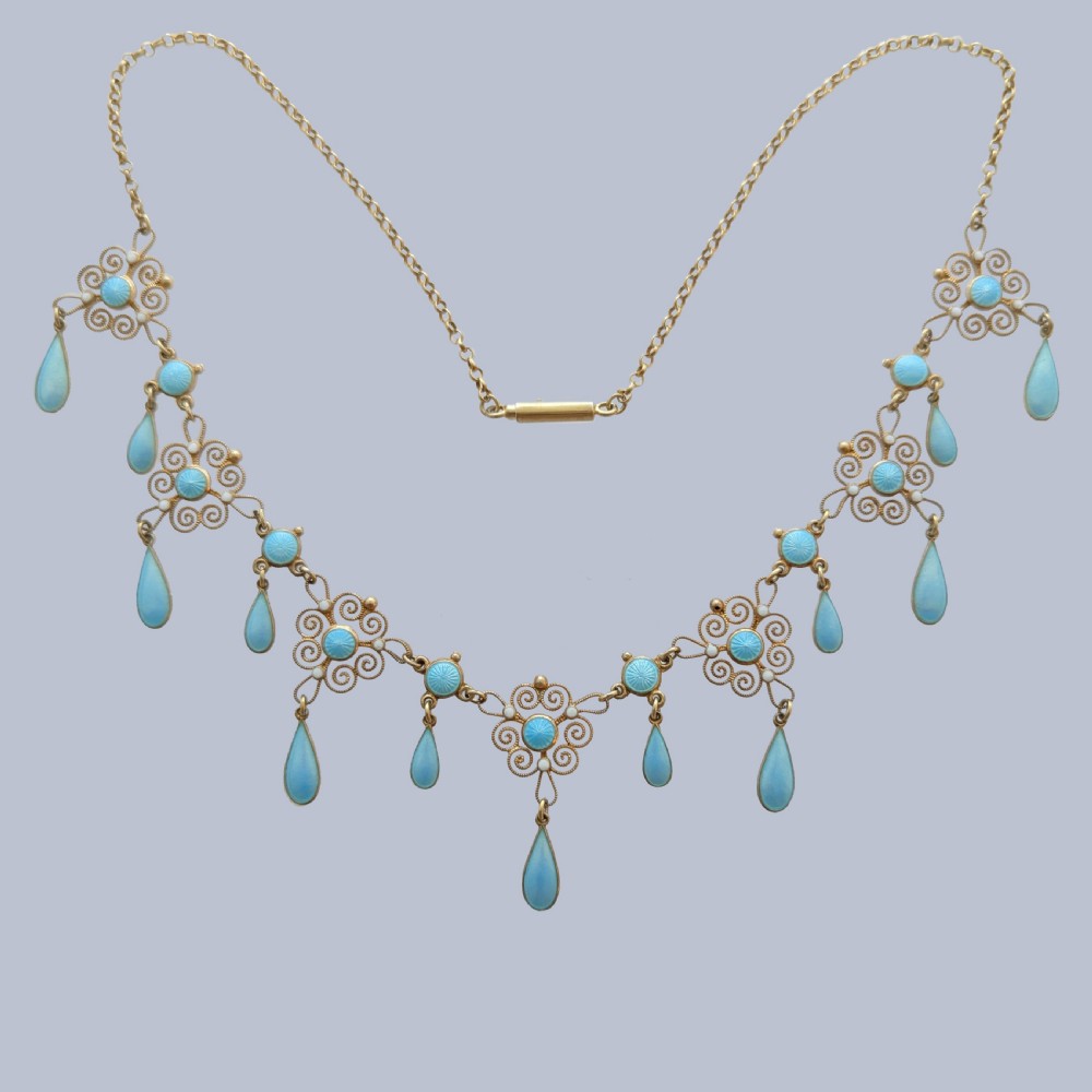 An Art Nouveau silver gilt festoon necklace featuring filigree scrollwork, turquoise guilloche enamel discs, and suspended teardrop pendants.