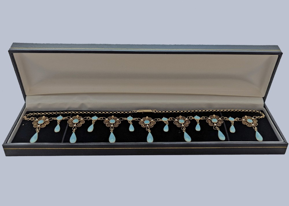 An Art Nouveau silver gilt festoon necklace featuring filigree scrollwork, turquoise guilloche enamel discs, and suspended teardrop pendants. View VII