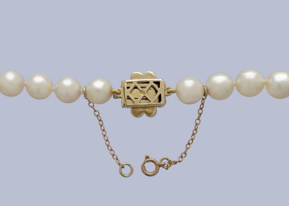 A long single strand of creamy white cultured pearls featuring a 9ct gold flower cluster clasp set with a central purple amethyst. View IV