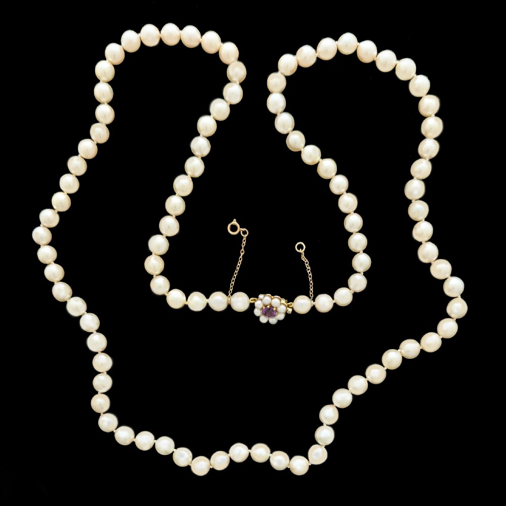 A long single strand of creamy white cultured pearls featuring a 9ct gold flower cluster clasp set with a central purple amethyst. View VI