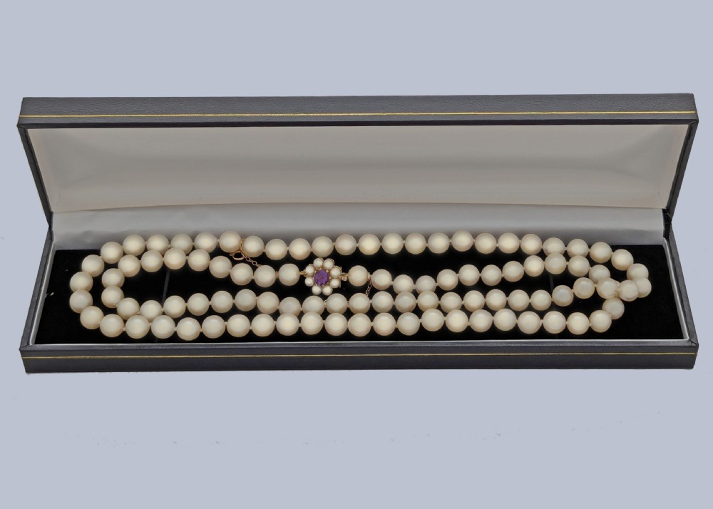 A long single strand of creamy white cultured pearls featuring a 9ct gold flower cluster clasp set with a central purple amethyst. View VII