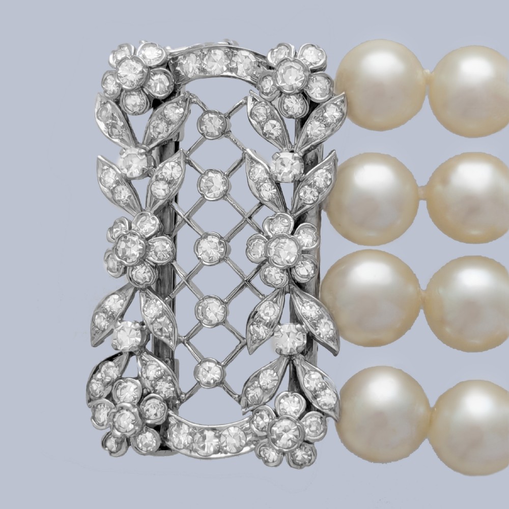 An Edwardian four-strand pearl bracelet featuring a central openwork diamond floral clasp in white metal. View III