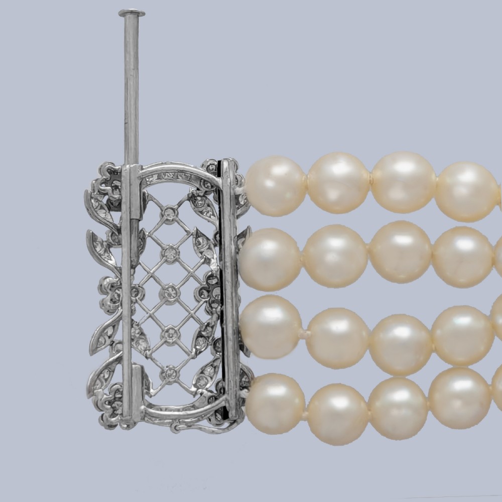 An Edwardian four-strand pearl bracelet featuring a central openwork diamond floral clasp in white metal. View IV