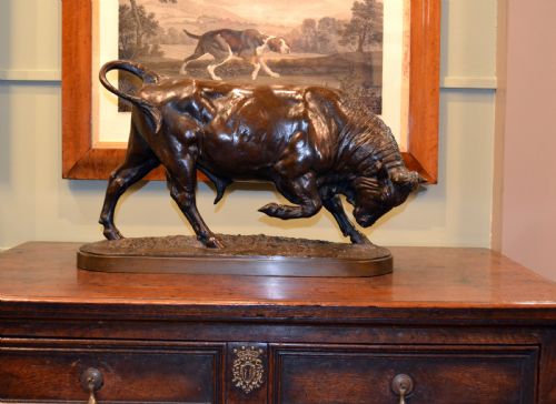 fig 1. A dark patinated bronze sculpture depicting a muscular charging bull on an integral oval bronze base.