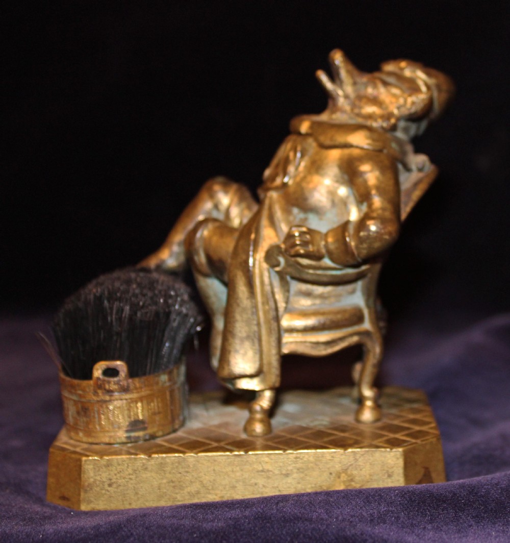 An antique gilt bronze desk accessory depicting an anthropomorphic fox wearing a nightgown and nightcap seated in an armchair with his foot resting on a bristle pen wiper. View III