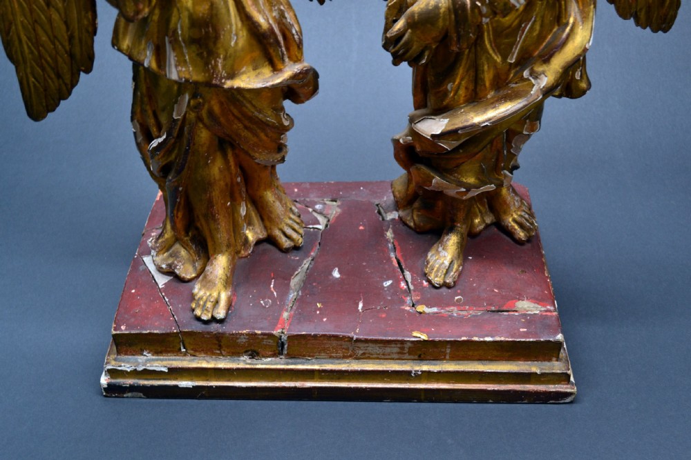 Two antique carved wooden figures of archangels with large wings, finished in distressed gold leaf and standing on a red-painted rectangular base. View V