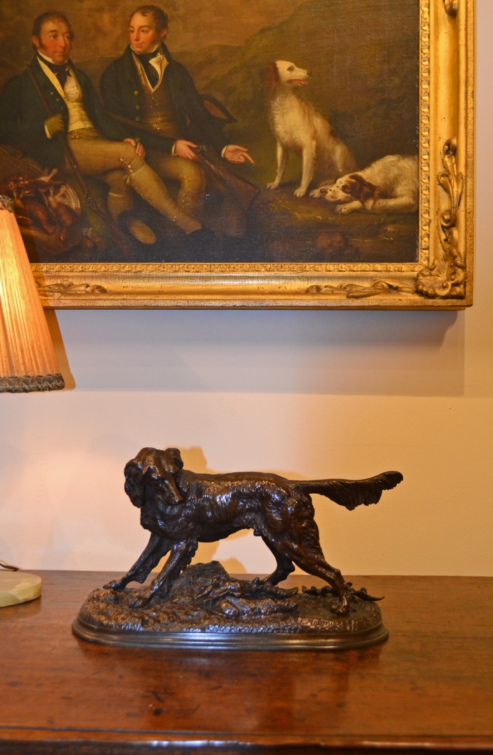 A dark brown patinated bronze sculpture depicting a setter dog standing over a rabbit on a textured ground base. View IV