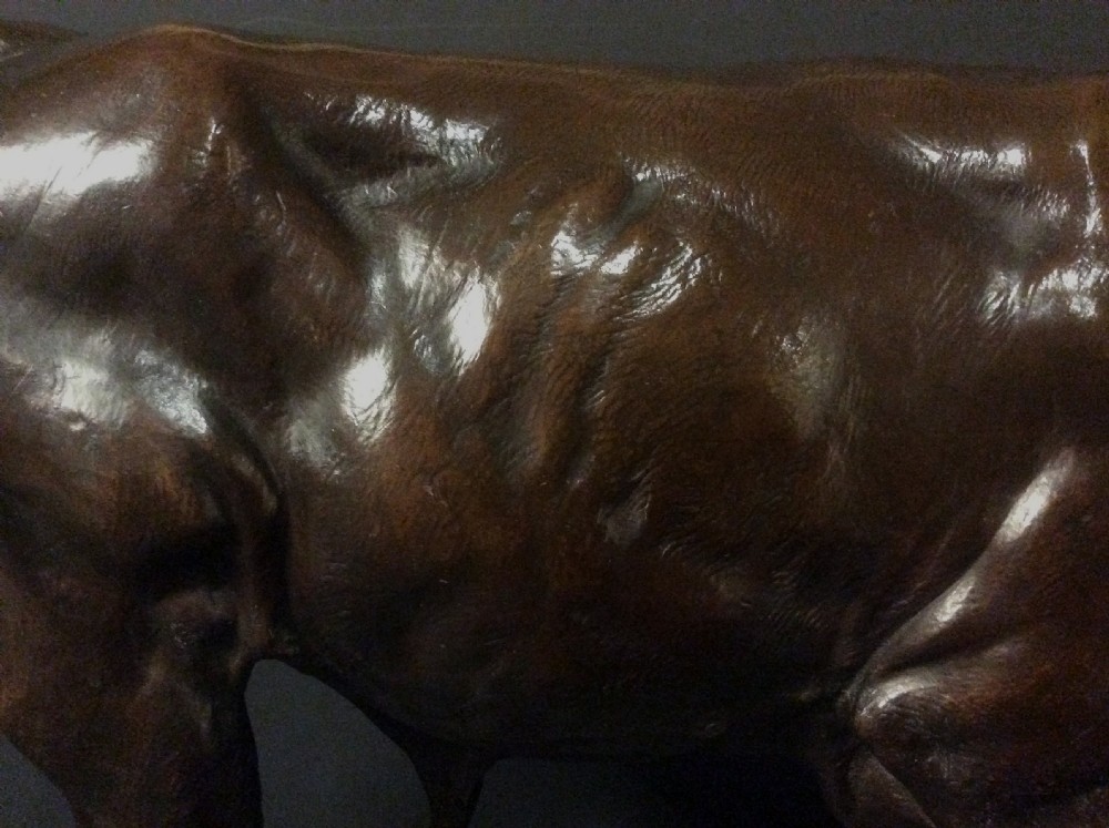 A dark patinated bronze sculpture depicting a muscular charging bull on an integral oval bronze base. View IV