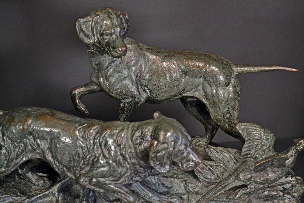 A 19th-century dark bronze sculpture depicting two gundogs flushing a pheasant, set upon a naturalistic base and mounted on a dark green marble plinth. View II