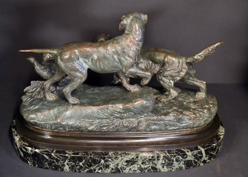 A 19th-century dark bronze sculpture depicting two gundogs flushing a pheasant, set upon a naturalistic base and mounted on a dark green marble plinth. View III