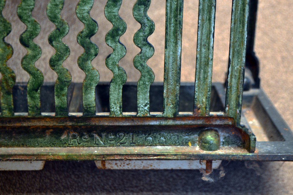 A black cast iron stick stand featuring a central relief figure of a nineteenth-century footballer holding a ball, framed by scrolling detail and twin drip trays. View VI