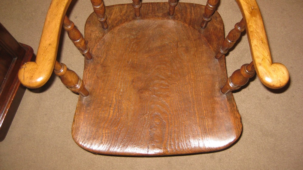 A late Victorian wooden Captains armchair with a curved backrest, turned spindles, and a contoured seat. View II