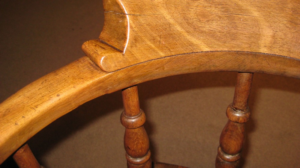 A late Victorian wooden Captains armchair with a curved backrest, turned spindles, and a contoured seat. View III