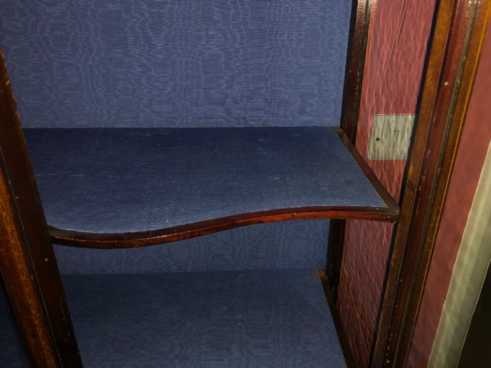 A late Victorian mahogany glazed display cabinet featuring three central glass doors above geometric inlaid timber panels, resting on cabriole legs with a blue fabric-lined interior. View III