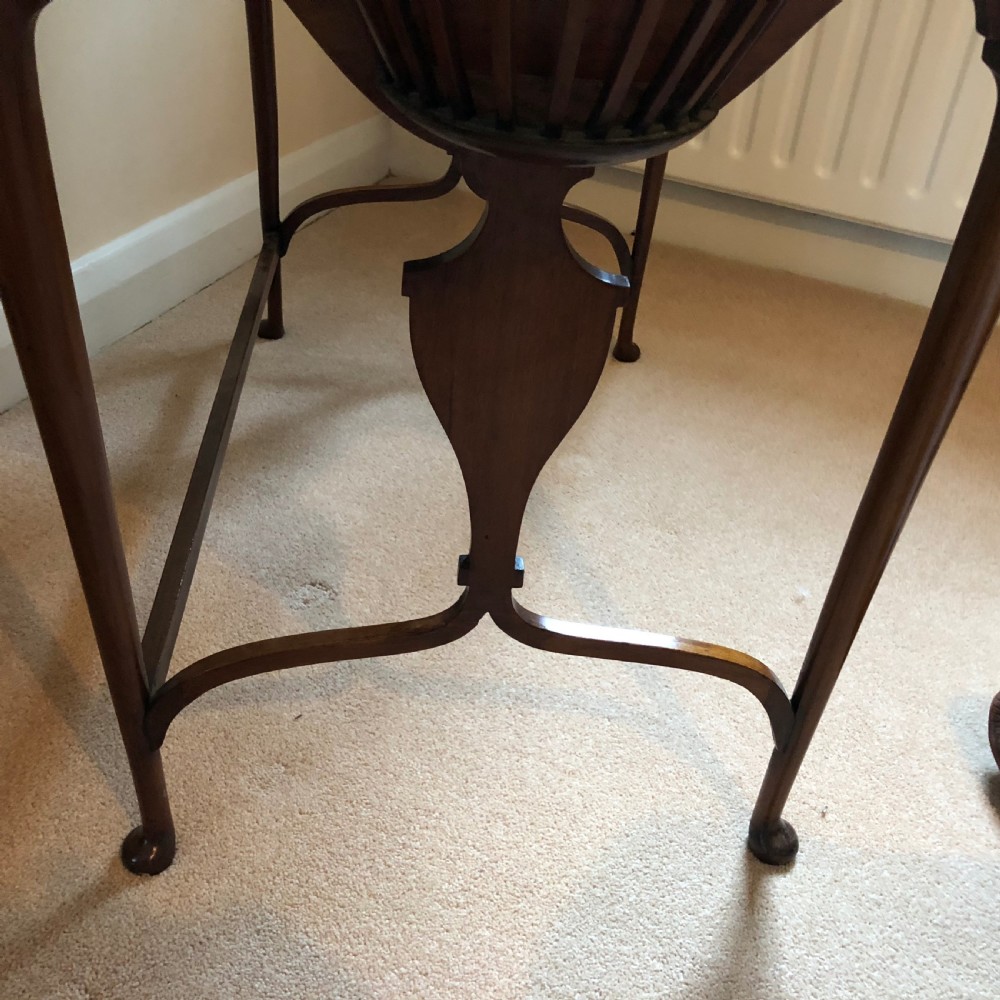 A late Victorian mahogany writing table featuring a shaped red leather inset writing surface, integrated inkwell compartments, and spindle-turned side galleries supported by slender cabriole legs. View II
