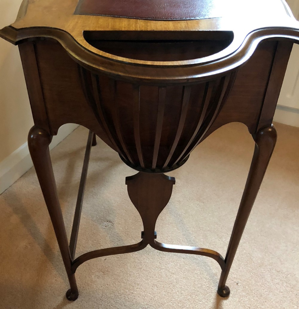 A late Victorian mahogany writing table featuring a shaped red leather inset writing surface, integrated inkwell compartments, and spindle-turned side galleries supported by slender cabriole legs. View III