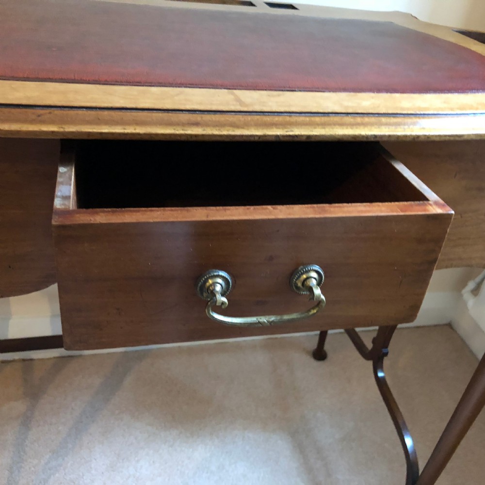 A late Victorian mahogany writing table featuring a shaped red leather inset writing surface, integrated inkwell compartments, and spindle-turned side galleries supported by slender cabriole legs. View IV