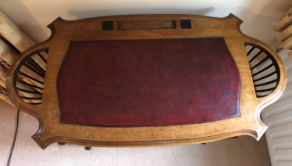 A late Victorian mahogany writing table featuring a shaped red leather inset writing surface, integrated inkwell compartments, and spindle-turned side galleries supported by slender cabriole legs. View VI