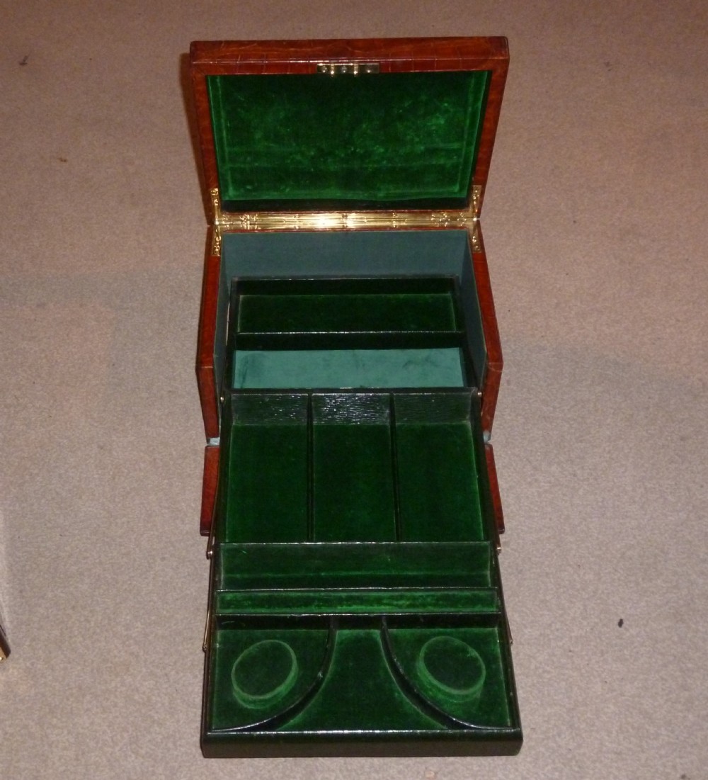 A rectangular warm brown crocodile leather jewellery case featuring a flush recessed brass handle on top and a brass lock keyhole on the front. View III