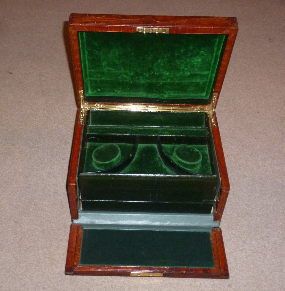 A rectangular warm brown crocodile leather jewellery case featuring a flush recessed brass handle on top and a brass lock keyhole on the front. View IV