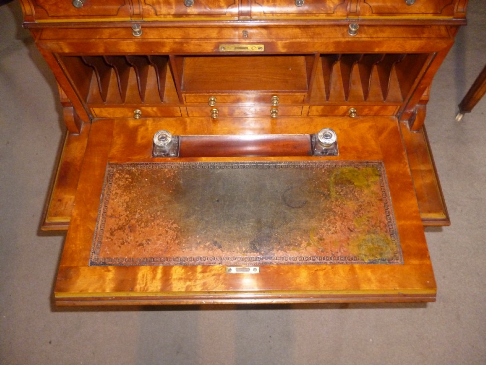 An Edwardian satinwood rolltop bureau featuring a cylinder front with an oval marquetry panel, a brass gallery rail top, and tapered legs. View VII