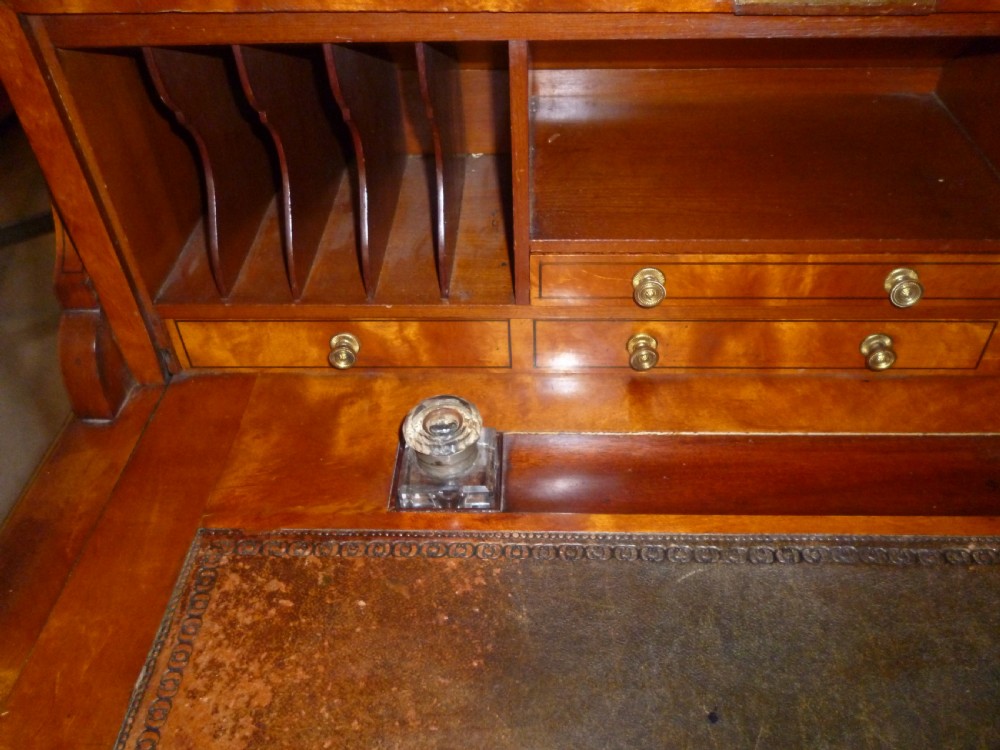 An Edwardian satinwood rolltop bureau featuring a cylinder front with an oval marquetry panel, a brass gallery rail top, and tapered legs. View VIII