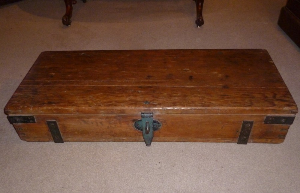 A low rectangular solid pine ammunition box featuring dark metal corner brackets and a central front latch.