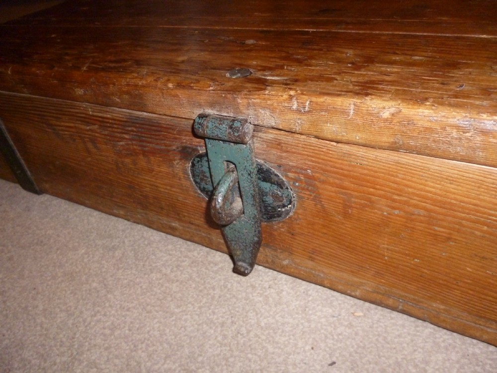 A low rectangular solid pine ammunition box featuring dark metal corner brackets and a central front latch. View II