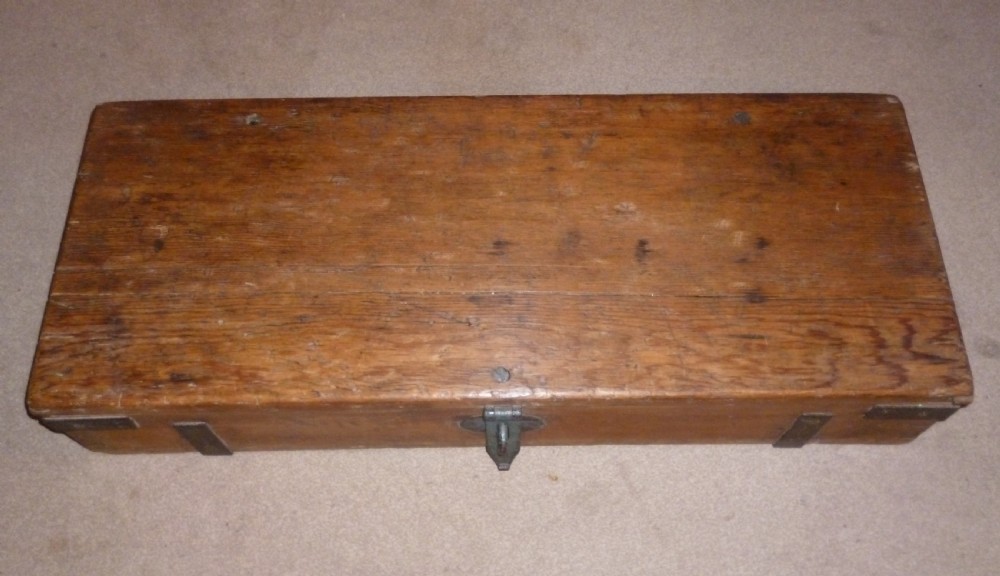 A low rectangular solid pine ammunition box featuring dark metal corner brackets and a central front latch. View IV