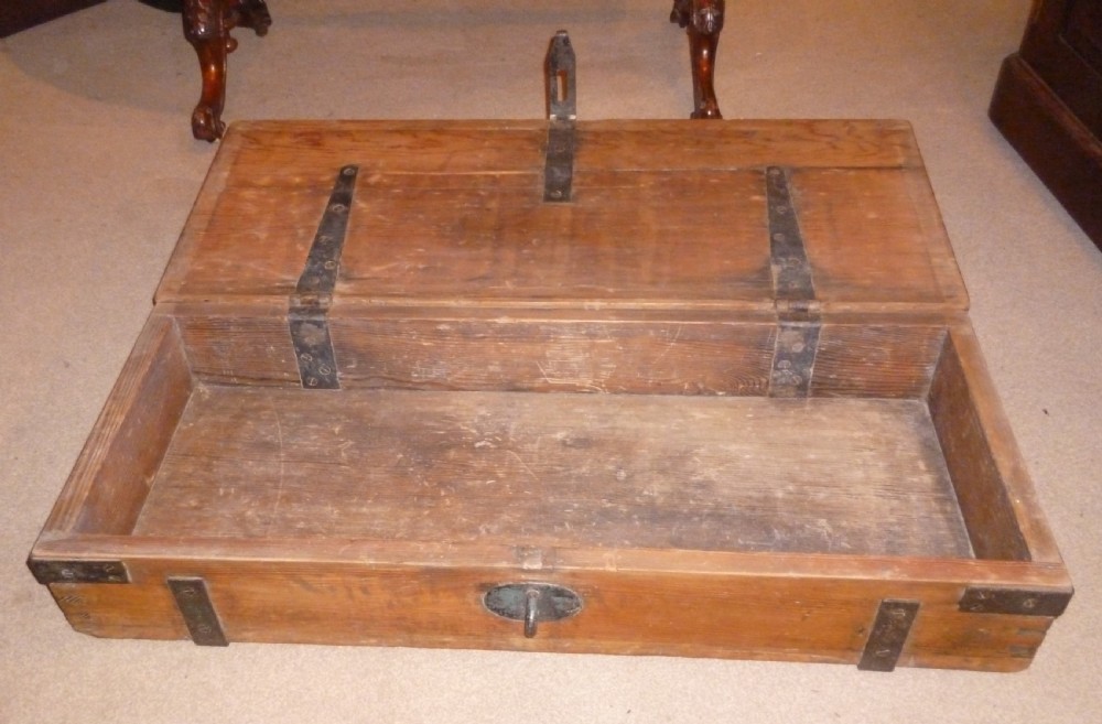 A low rectangular solid pine ammunition box featuring dark metal corner brackets and a central front latch. View V