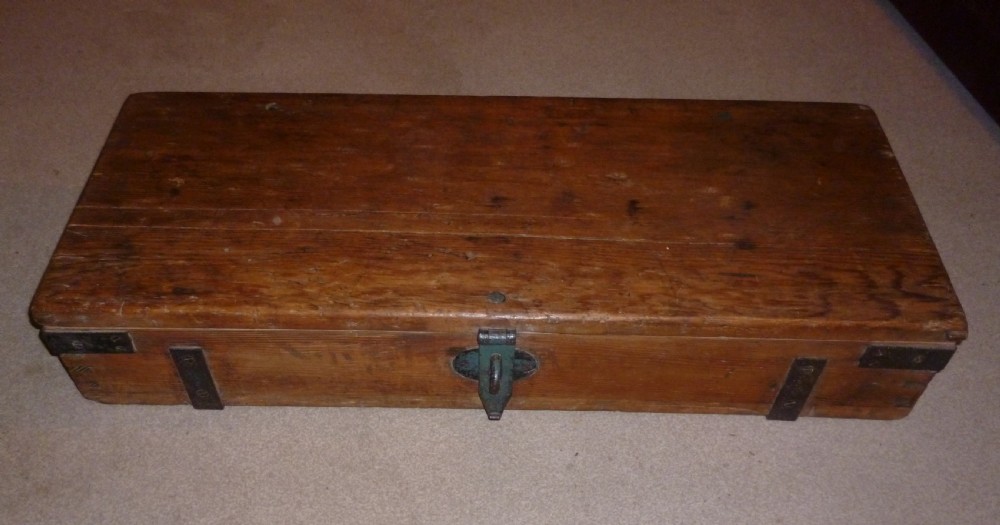 A low rectangular solid pine ammunition box featuring dark metal corner brackets and a central front latch. View VII