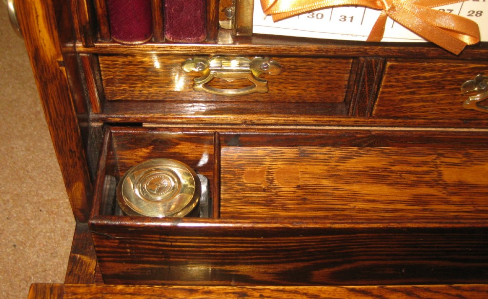 A late Victorian golden oak drop-front stationery cabinet featuring a brass keyhole and an engraved metal presentation shield on the top lid. View II