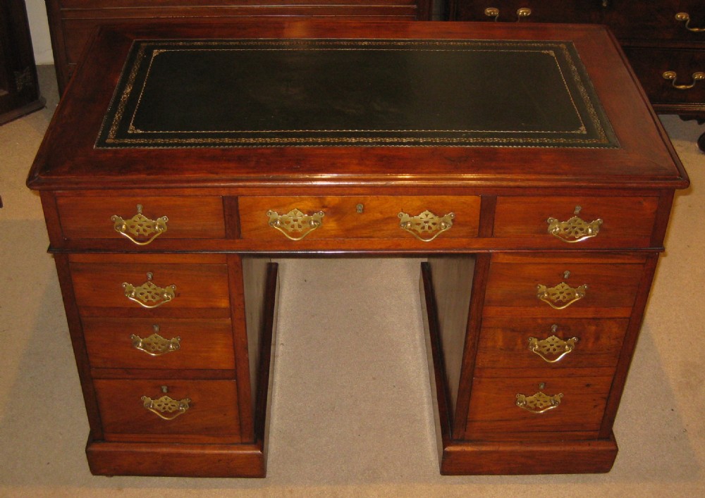 A Victorian walnut pedestal desk featuring nine drawers with decorative brass handles and a dark leather inset writing top. View II