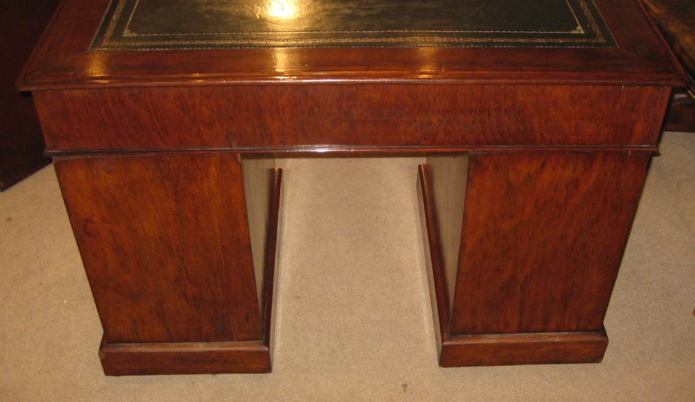 A Victorian walnut pedestal desk featuring nine drawers with decorative brass handles and a dark leather inset writing top. View III