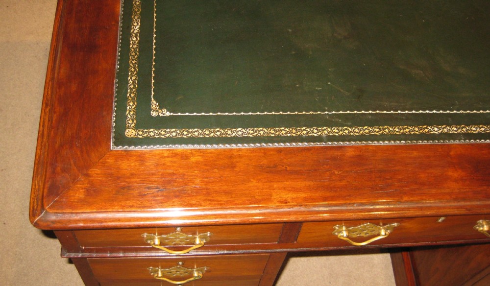 A Victorian walnut pedestal desk featuring nine drawers with decorative brass handles and a dark leather inset writing top. View V