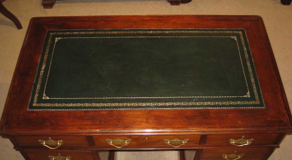 A Victorian walnut pedestal desk featuring nine drawers with decorative brass handles and a dark leather inset writing top. View X