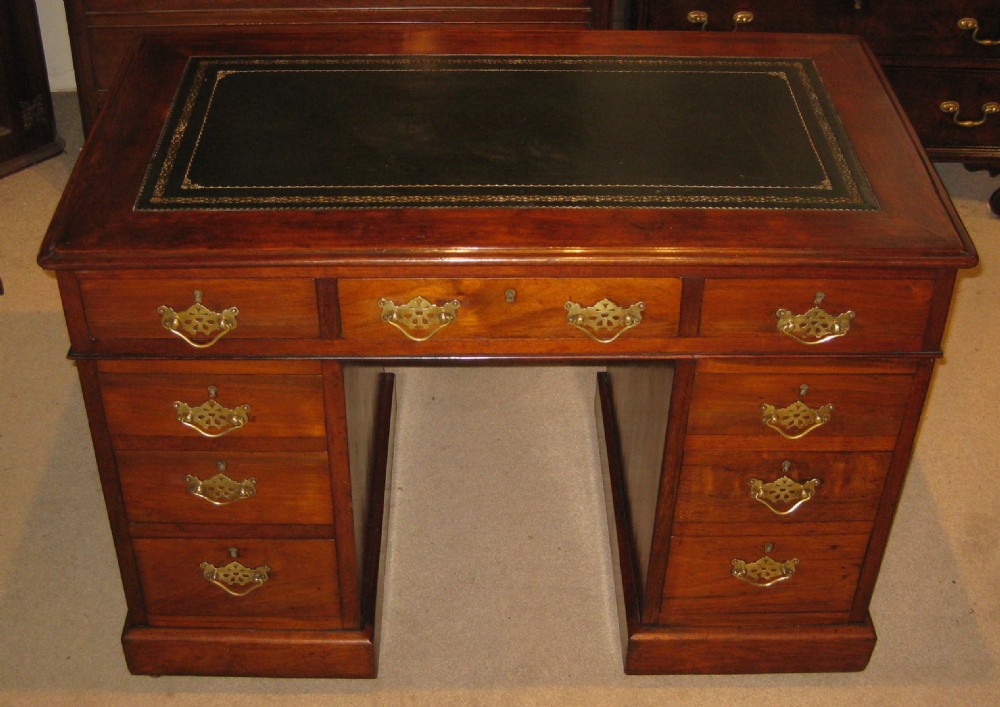 A Victorian walnut pedestal desk featuring nine drawers with decorative brass handles and a dark leather inset writing top.